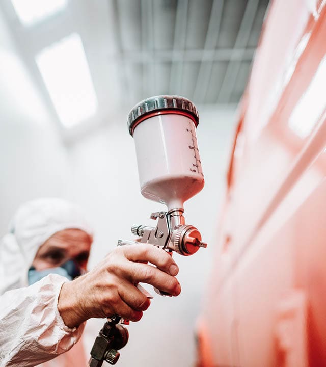 close up of paint spray gun, worker painting a car