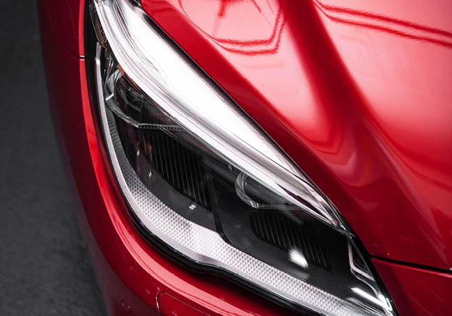 Back headlight of a modern luxury red car, auto detail, car care concept in the garage